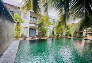 una piscina di fronte a un edificio con palme di Central Corner Suite a Siem Reap
