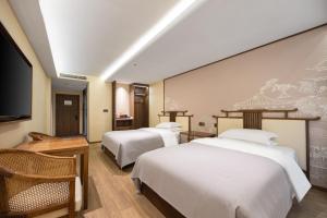 a hotel room with two beds and a flat screen tv at Honglu Garden Hotel Xi'an Bell and Drum Tower Huimin Street Store in Xi'an