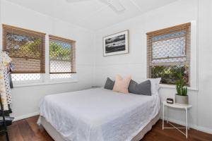 Un dormitorio blanco con una cama y dos ventanas. en Beach Pad close to Airport and Iconic Kirra Beach, en Gold Coast