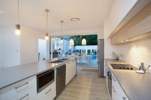 eine große Küche mit weißen Arbeitsflächen und einem großen Fenster in der Unterkunft Contemporary Coastal Luxury with an Outdoor Pool in Gold Coast
