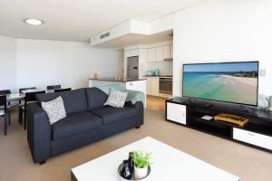 uma sala de estar com um sofá e uma televisão de ecrã plano em Luxe High-rise with Al Fresco Dining & Ocean views em Gold Coast
