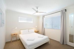 a white bedroom with a bed and a window at Beautiful Burleigh - Contemporary Beachside Retreat in Gold Coast