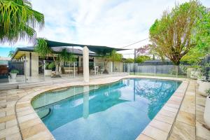 uma piscina em frente a uma casa em Sunny Days Poolside at an Entertainer's Oasis em Gold Coast