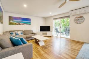 uma sala de estar com um sofá e uma televisão em Poolside Paradise Grove at Burleigh Heads em Gold Coast
