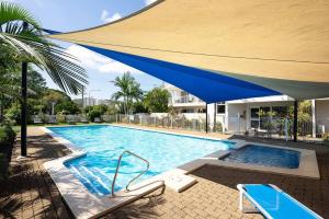 uma grande piscina azul com um grande guarda-chuva azul em Poolside Paradise Grove at Burleigh Heads em Gold Coast