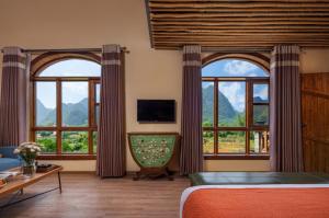 a bedroom with large windows with a view of mountains at Yangshuo Coco Garden Hotel in Yangshuo