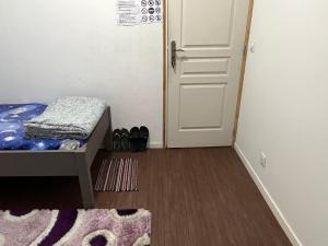 Pokój z łóżkiem, drzwiami i dywanem w obiekcie CHAMBRE PARTAGE 15MN CDG 25MN PARIS w Villepinte