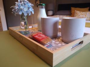 a wooden tray with two cups and a bottle on a table at Y Cuddfan Gower in Swansea