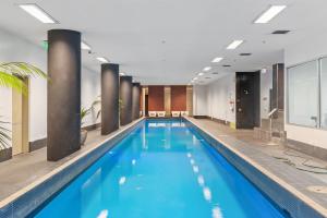a large swimming pool with blue water in a building at Resort Style Living Yarra Wharf in Melbourne