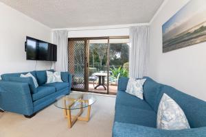ein Wohnzimmer mit zwei blauen Sofas und einem Glastisch in der Unterkunft Oceancrest 4 in Forster