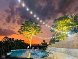 une corde de lumière sur une piscine au coucher du soleil dans l'établissement Mây Trắng Farmstay Villas Venuestay, à Ba Vì