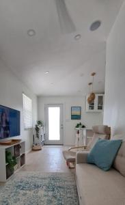 a white living room with a couch and a window at Conch Club Cottage in Head of Bay