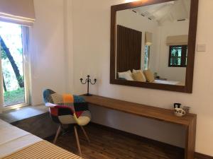 1 dormitorio con espejo, silla y cama en River Garden Resort, en Belihuloya