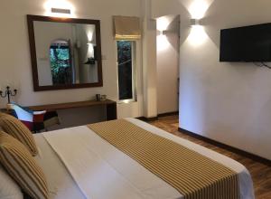 een slaapkamer met een bed en een flatscreen-tv bij River Garden Resort in Belihul Oya