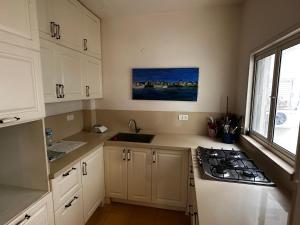 a kitchen with white cabinets and a sink and a stove at Family Park apartment with 2 bedrooms in Tel Aviv