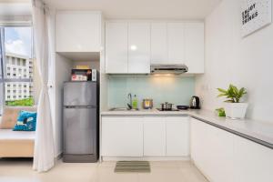 eine Küche mit weißen Schränken und einem Kühlschrank aus Edelstahl in der Unterkunft TRESOR POOL GYM, THE TROPICAL STUDIO IN CENTER in Ho-Chi-Minh-Stadt
