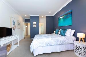a bedroom with a large bed and a flat screen tv at Gwydir Court 1 in Forster