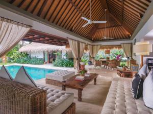 an open living room with a pool and furniture at The One Boutique Villa in Seminyak