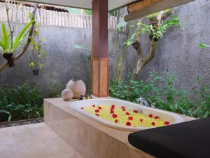 a bathroom with a tub with flowers in it at The One Boutique Villa & Spa Seminyak in Seminyak +95 photos