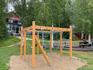 a playground with a wooden swing set in a park at Hotel Rantakatti in Punkaharju
