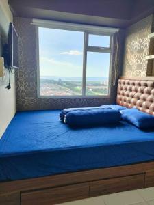 a bedroom with a large blue bed with a window at Apartemen Educity Pakuwon city Surabaya BACA DESKRIPSI DULU in Surabaya
