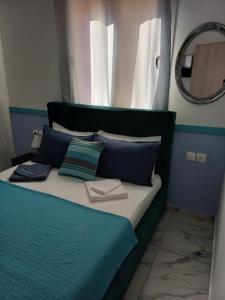 a bed with blue and white pillows and a mirror at Hari Apartments Vathi, Agios Nikolaos Crete in Vathi