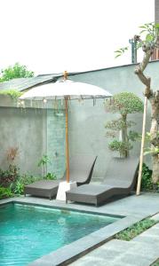 a swimming pool with two chairs and an umbrella at Santera Village in Canggu