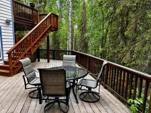 a patio with a table and chairs on a deck at Guest Suite with Hot Tub - Edge of the Wild in Eagle River