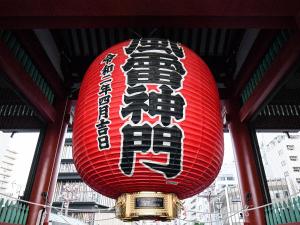 une lanterne rouge avec écriture suspendue à un bâtiment dans l'établissement Vessel Inn Asakusa Tsukuba Express, à Tokyo
