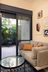 uma sala de estar com um sofá e uma mesa de vidro em Classy 1 BR Apt w Private Balcony By Sea N' Rent em Tel Aviv