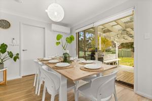 a dining room with a wooden table and chairs at Berry Haven by Experience Jervis Bay in Vincentia