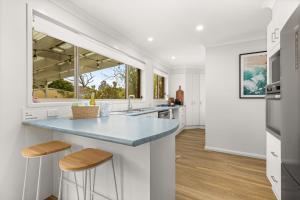 a kitchen with white walls and a blue counter top at Berry Haven by Experience Jervis Bay in Vincentia +14 photos