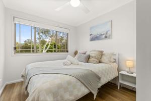 a white bedroom with a bed and a window at Berry Haven by Experience Jervis Bay in Vincentia