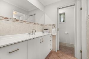 a white bathroom with a sink and a mirror at Berry Haven by Experience Jervis Bay in Vincentia