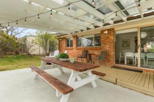 a patio with a wooden table and a bench at Berry Haven by Experience Jervis Bay in Vincentia