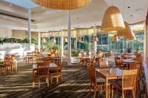 un restaurante con mesas y sillas de madera y ventanas grandes en Club Wyndham Coffs Harbour Terraces, en Coffs Harbour