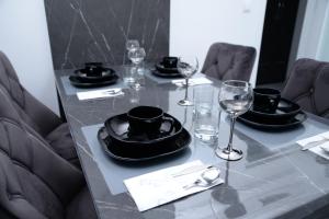 ITACA apartman Krupanj في Krupanj: طاولة عليها أطباق سوداء واكواب للنبيذ