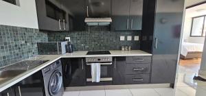 a kitchen with black cabinets and a washer and dryer at Cozy Retreat in Windhoek in Windhoek