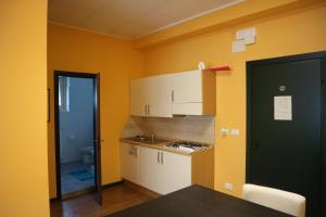 Una cocina con paredes amarillas y gabinetes blancos y una puerta en Cave Trieste Apartments - CaTs Apartments, en Tarvisio