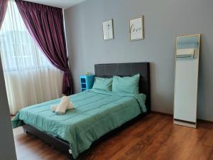 a bedroom with a bed with a green comforter at Viva city Jazz3 Homestay Near Tabuan Jaya in Kuching