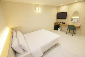 a room with a bed and a desk with a television at Chuncheon Pine Tree Hotel in Chuncheon