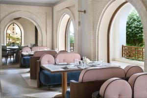 InterContinental Durrat Al Riyadh Resort & Spa, an IHG Hotel في الرياض: مطعم فيه كراسي وردية وطاولات وقووس