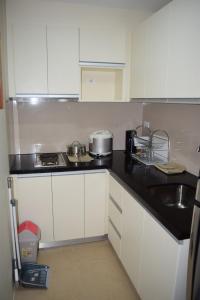 a kitchen with white cabinets and a black counter top at Consuelo Boracay Unit Rental in Boracay
