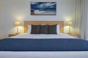 Club Wyndham Port Macquarie في ميناء ماكواري: غرفة نوم بسرير وبطانية زرقاء ومصباحين