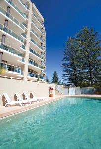 a swimming pool with two lounge chairs and a building at Club Wyndham Port Macquarie in Port Macquarie