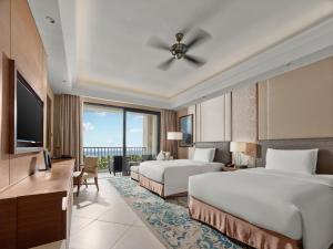 a hotel room with two beds and a flat screen tv at Hilton Haikou Meilan - Beachfront Hotel in Haikou