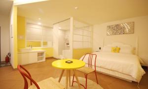 a bedroom with a bed and a yellow table and chairs at Iksan 4 Seasons Hotel in Iksan