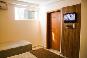 a room with two beds and a television on a door at Hotel Saint Martin in Bauru