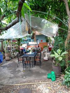 un patio con mesa y sillas bajo un dosel en Baanchaokoh Homestay en Kanchanaburi