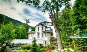 a large white house in the middle of a forest at Abastumani Residence in Abastumani